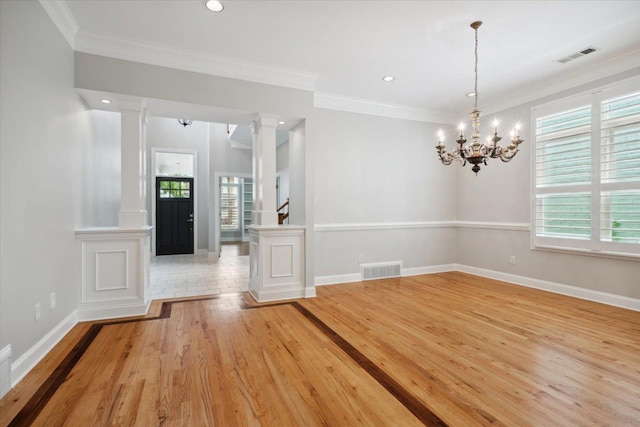 spare room with ornamental molding, a wealth of natural light, light hardwood / wood-style floors, and ornate columns