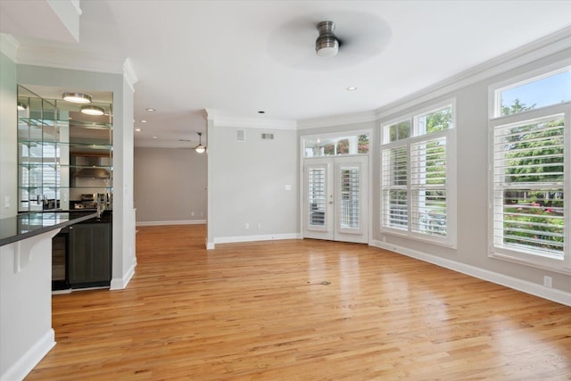 unfurnished living room with ornamental molding, french doors, ceiling fan, and light wood-type flooring