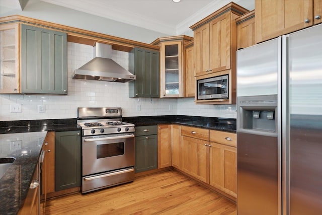 kitchen featuring stainless steel appliances, crown molding, wall chimney range hood, and decorative backsplash