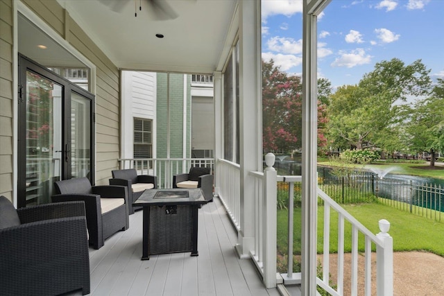 sunroom featuring a water view and ceiling fan