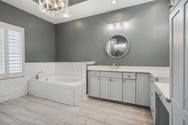 bathroom featuring vanity, tiled bath, and a chandelier