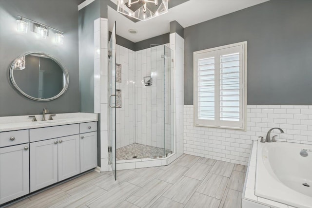 bathroom with vanity, tile walls, and separate shower and tub