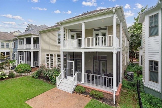 back of house with a balcony, a sunroom, central AC, and a lawn