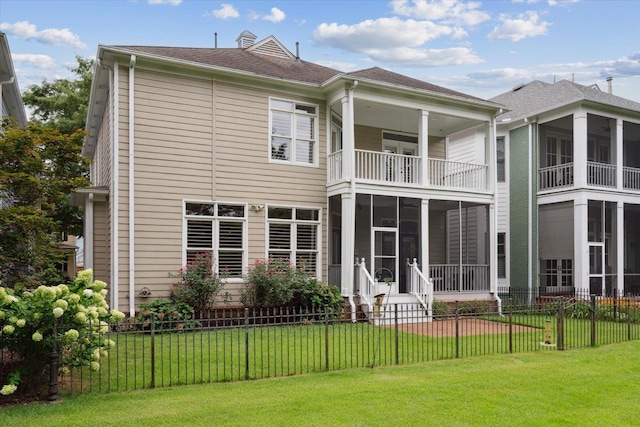 rear view of house featuring a balcony, a sunroom, and a lawn