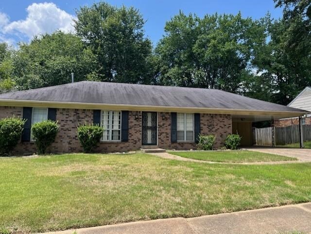 ranch-style home featuring a front lawn and a carport