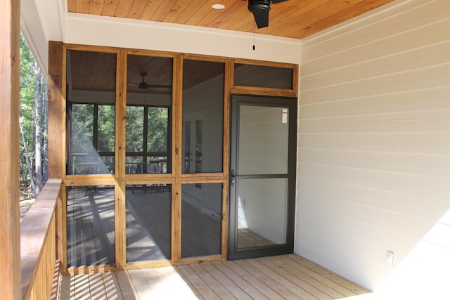 unfurnished sunroom featuring wood ceiling, a wealth of natural light, and ceiling fan