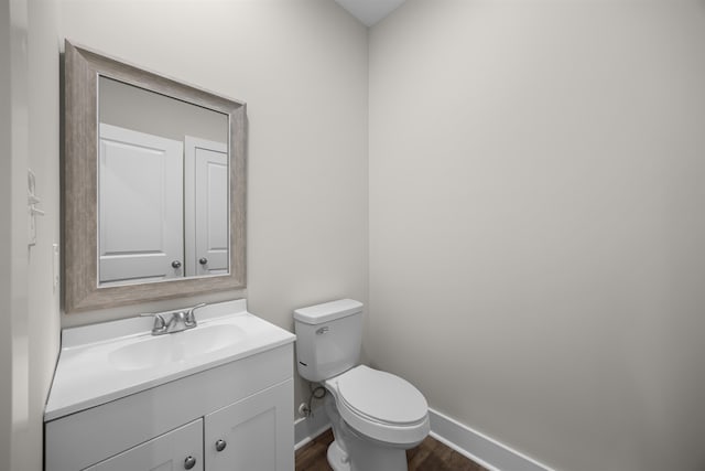 bathroom with toilet, vanity, and wood-type flooring