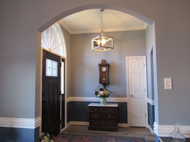 foyer featuring an inviting chandelier, ornamental molding, and hardwood / wood-style flooring