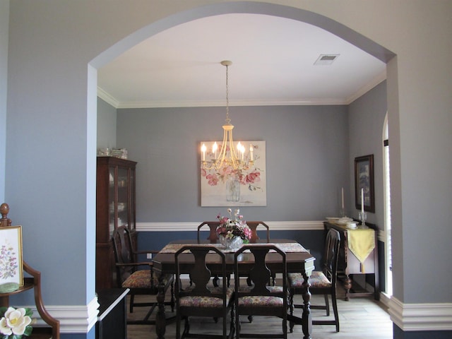 dining room with hardwood / wood-style floors, an inviting chandelier, and crown molding