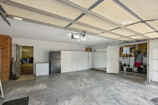 garage featuring black refrigerator, fridge, and a garage door opener