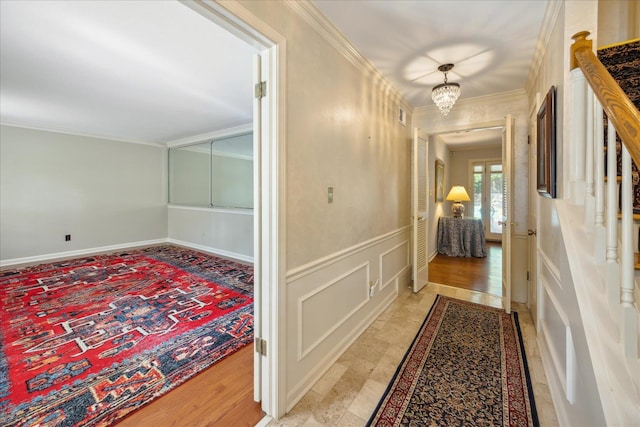 hall featuring an inviting chandelier, light hardwood / wood-style flooring, and ornamental molding