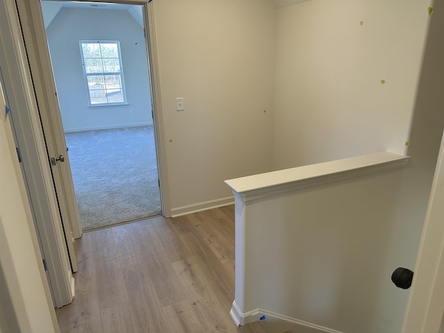 hall with vaulted ceiling and light hardwood / wood-style floors