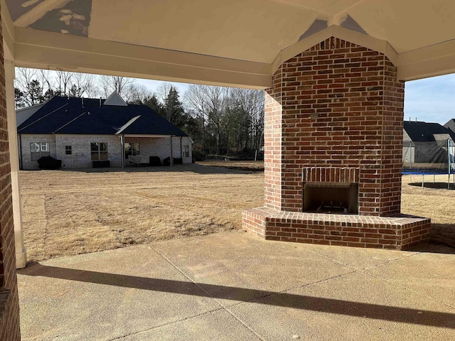 view of patio / terrace with an outdoor brick fireplace and a trampoline