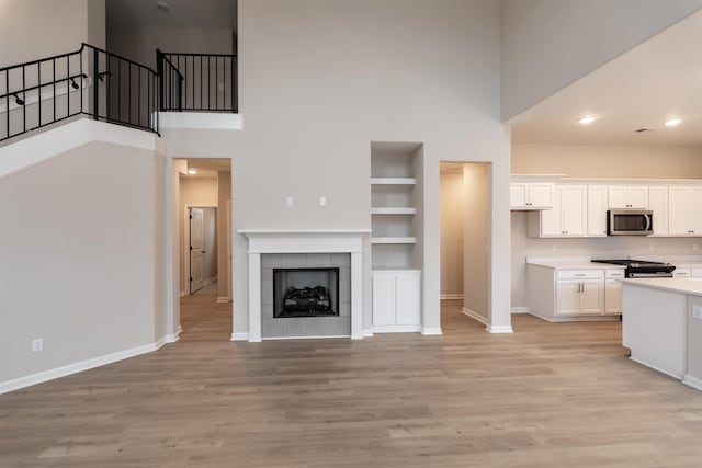 kitchen featuring stove, built in shelves, light hardwood / wood-style flooring, and white cabinets