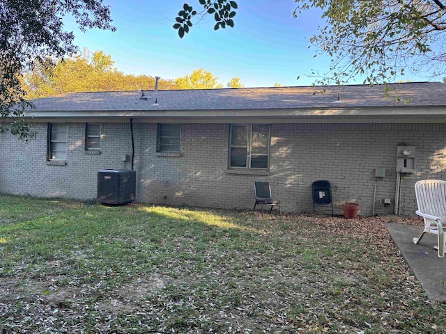 back of property with central AC and a yard