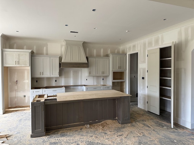 kitchen featuring gray cabinetry, a kitchen island, ornamental molding, and premium range hood