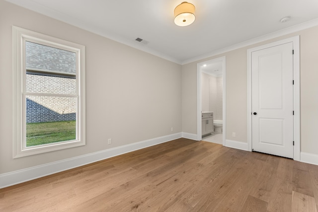 unfurnished bedroom with ornamental molding, light hardwood / wood-style floors, and ensuite bath