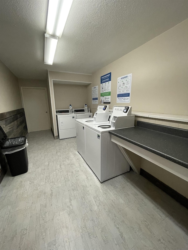 common laundry area featuring light wood finished floors, a textured ceiling, and independent washer and dryer