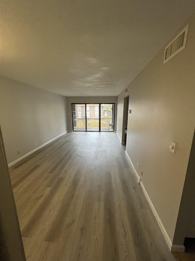 empty room with visible vents, baseboards, and wood finished floors