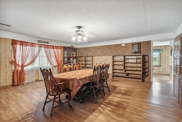 dining room with ornamental molding, hardwood / wood-style floors, and a textured ceiling