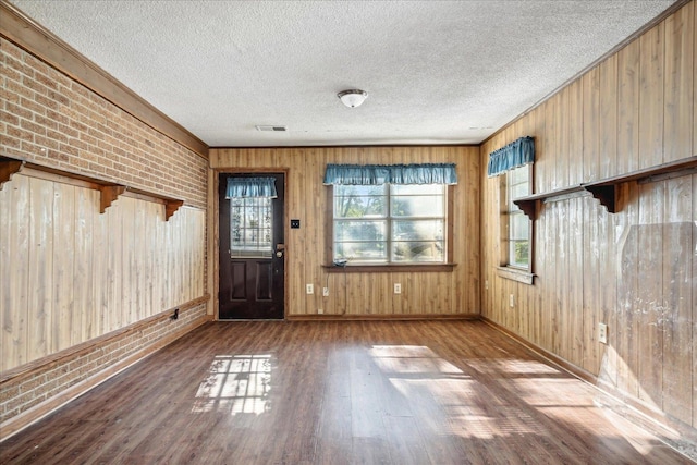 entryway with hardwood / wood-style flooring, a textured ceiling, and wood walls