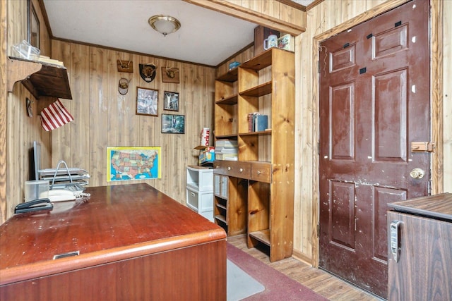 unfurnished office featuring ornamental molding, wood walls, and light wood-type flooring