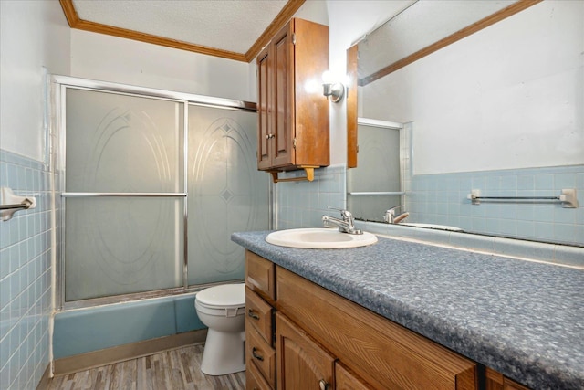 full bathroom with crown molding, shower / bath combination with glass door, tile walls, vanity, and hardwood / wood-style flooring