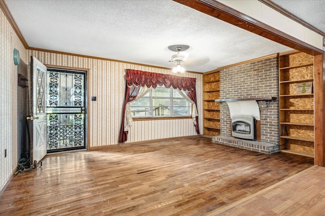 unfurnished living room with ornamental molding, a fireplace, wood-type flooring, and a textured ceiling