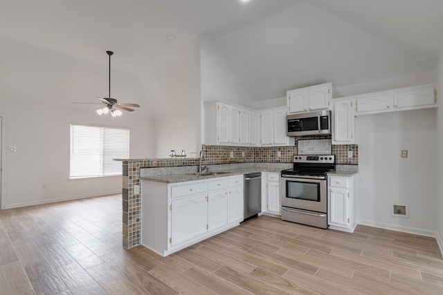 kitchen with white cabinets, backsplash, ceiling fan, appliances with stainless steel finishes, and high vaulted ceiling