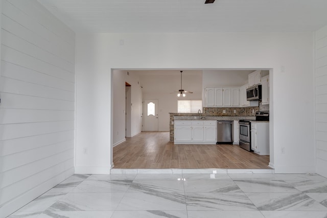 kitchen with white cabinetry, tasteful backsplash, light wood-type flooring, ceiling fan, and stainless steel appliances