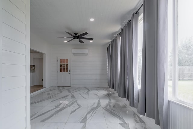 interior space with a wall mounted AC, light tile patterned flooring, and ceiling fan