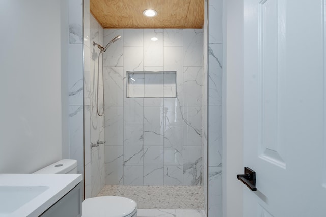 bathroom with vanity, tiled shower, and toilet