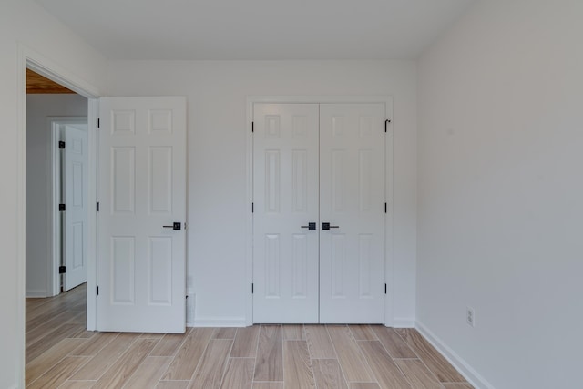 unfurnished bedroom featuring light wood-type flooring and a closet