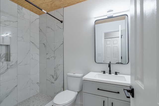 bathroom featuring vanity, tiled shower, and toilet