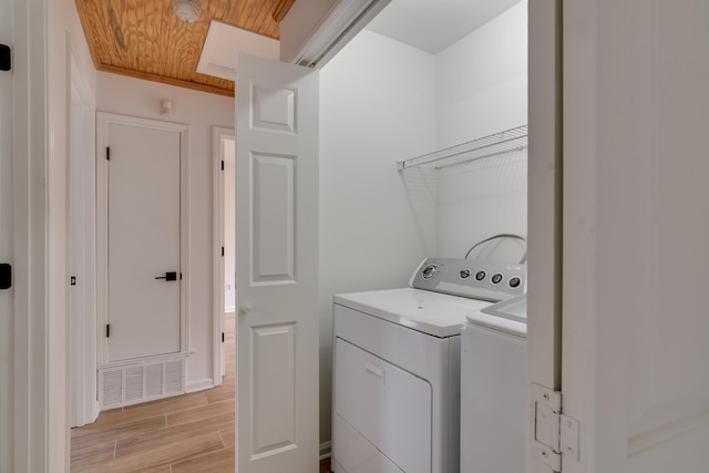 laundry room with light hardwood / wood-style floors, separate washer and dryer, and wooden ceiling