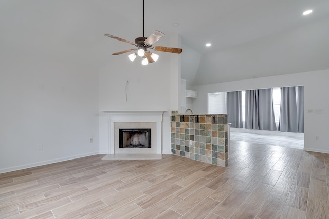 unfurnished living room featuring ceiling fan, light wood-type flooring, and high vaulted ceiling