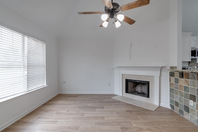 unfurnished living room with sink, light wood-type flooring, ceiling fan, and plenty of natural light