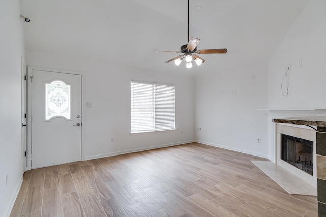 unfurnished living room with plenty of natural light, a high end fireplace, light wood-type flooring, and ceiling fan