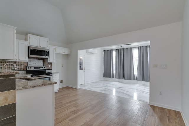 kitchen with white cabinetry, a wall mounted AC, light stone countertops, appliances with stainless steel finishes, and light hardwood / wood-style flooring