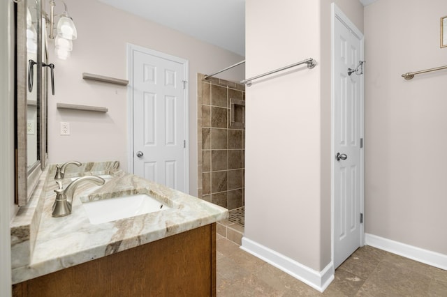 bathroom with tiled shower, vanity, and tile patterned flooring