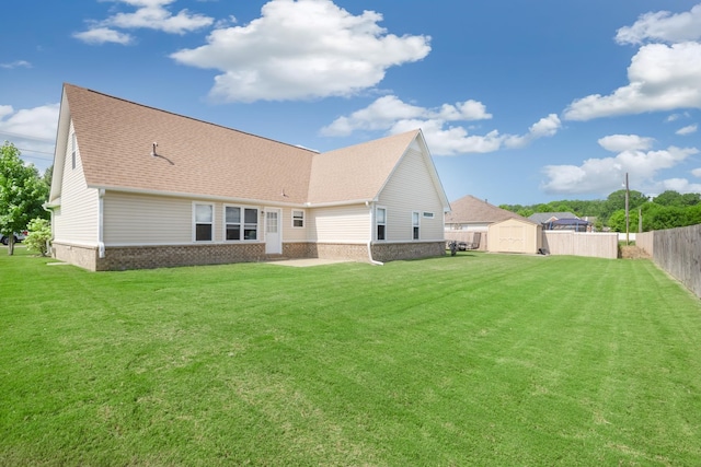 rear view of property with a storage shed and a yard