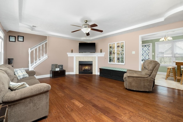 living room featuring a raised ceiling, a tiled fireplace, and hardwood / wood-style floors