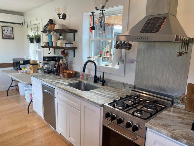 kitchen featuring an AC wall unit, white cabinets, range hood, stainless steel appliances, and sink