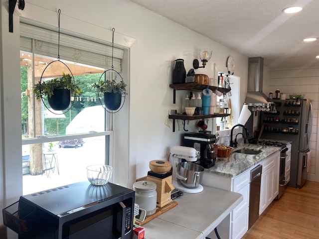 kitchen featuring white cabinets, stainless steel appliances, sink, light hardwood / wood-style floors, and wall chimney exhaust hood