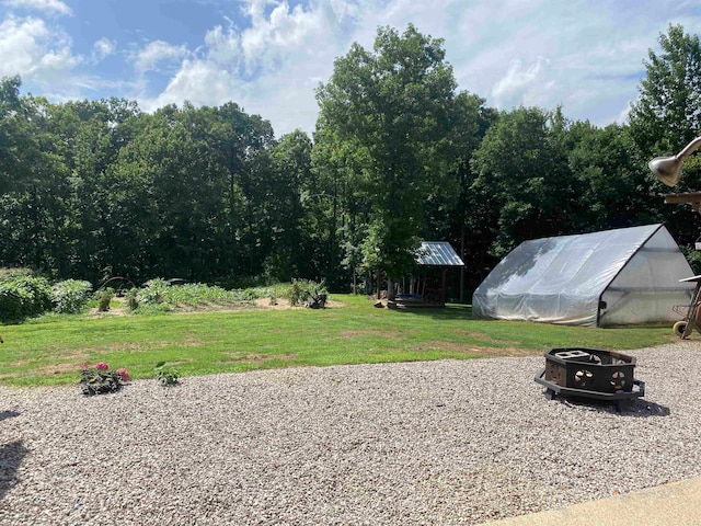 view of yard featuring an outdoor structure and an outdoor fire pit