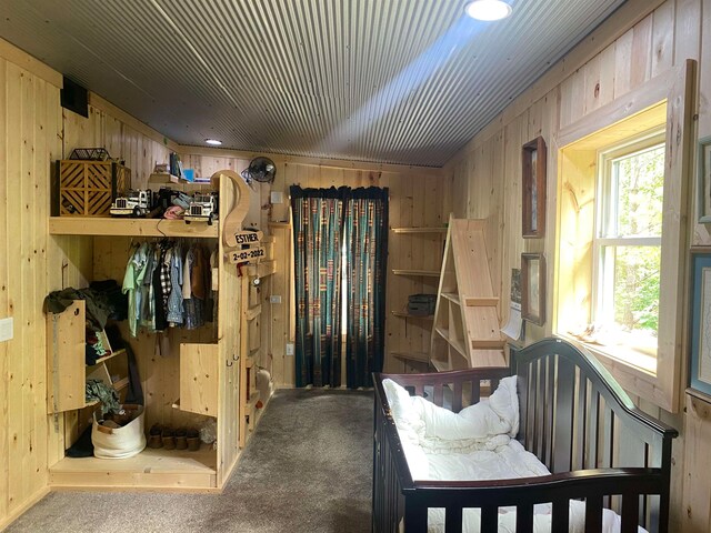 carpeted bedroom featuring wood walls