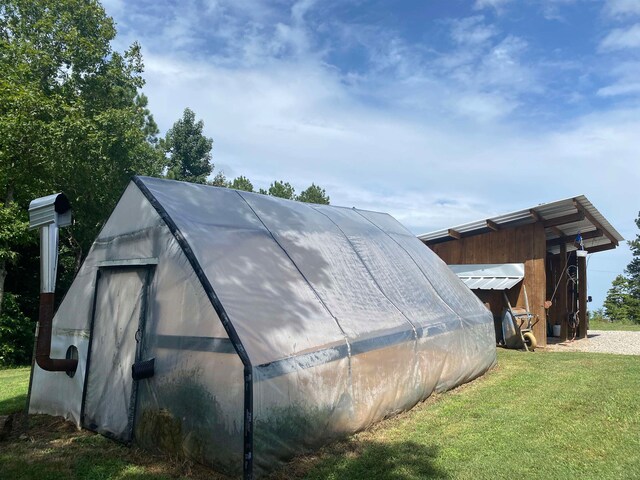 view of side of home featuring a lawn and an outbuilding