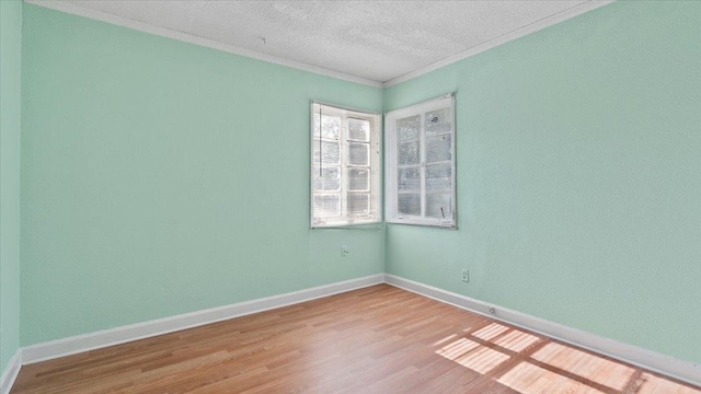 empty room featuring a textured ceiling, wood-type flooring, and ornamental molding