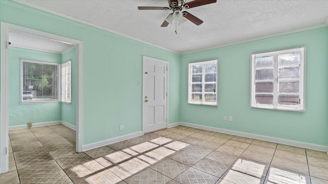 tiled spare room with ceiling fan, a wealth of natural light, and a textured ceiling