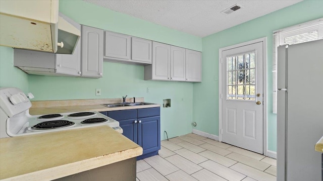 kitchen featuring light tile patterned flooring, white refrigerator, white cabinets, sink, and stove